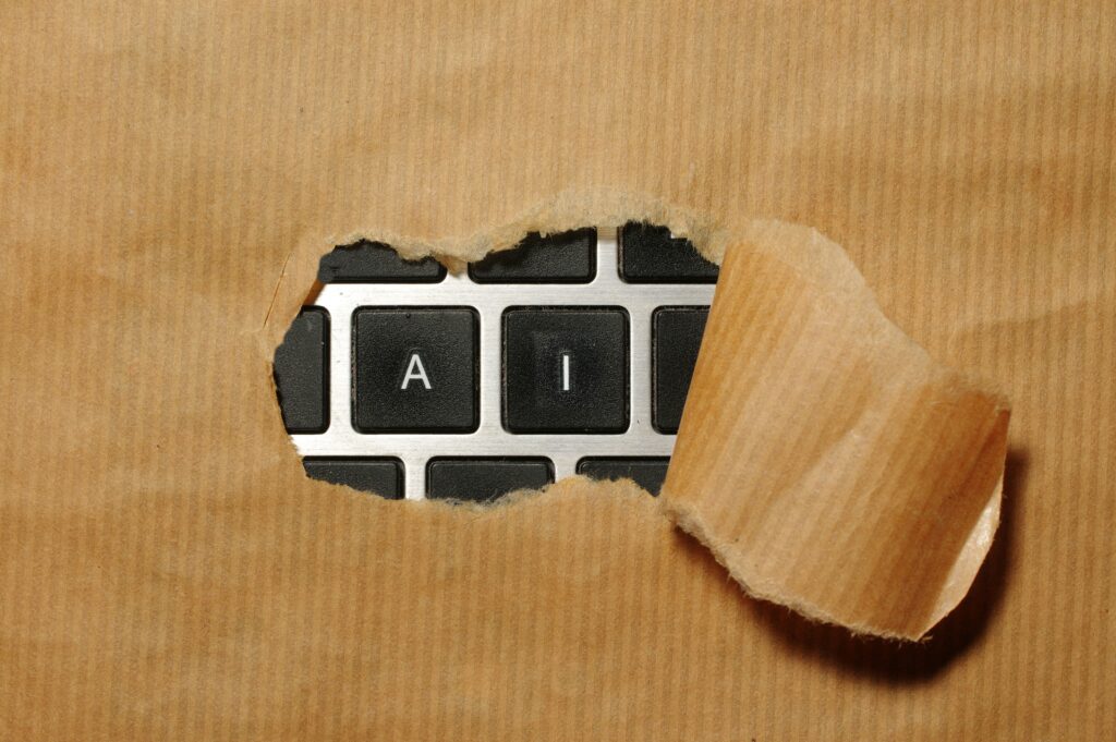 A torn piece of brown paper reveals a computer keyboard with the letters A and I visible, symbolizing artificial intelligence and its growing role in Brand Reputation Management.